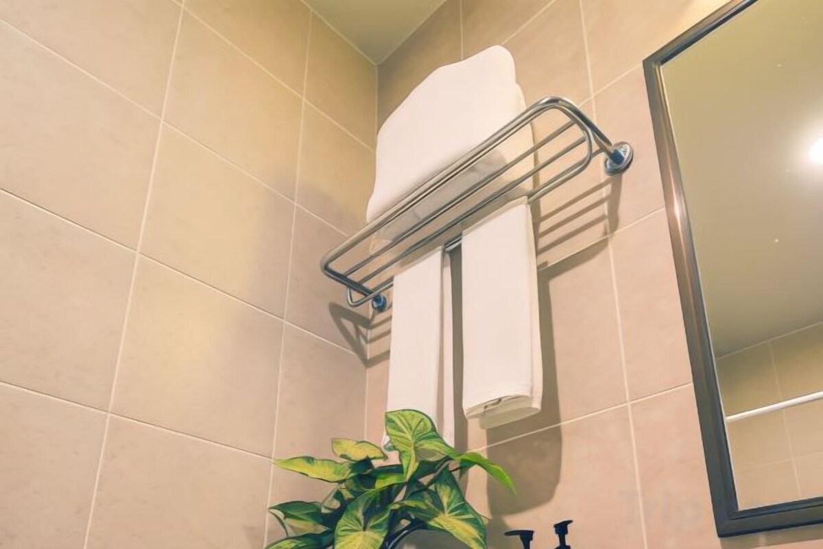 A bathroom with a towel rack, a mirror, and a potted plant.
