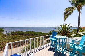 A deck with chairs and a table overlooking a body of water.