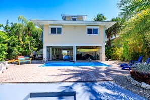 A two-story house with a swimming pool, covered patio, and outdoor seating area.