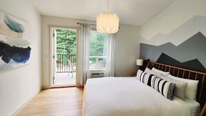 Quarto com cama, janela, pintura e vista para o verde.