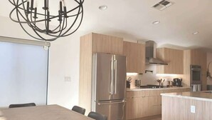Cocina moderna con una isla central, electrodomésticos de acero inoxidable y un comedor con mesa y sillas.