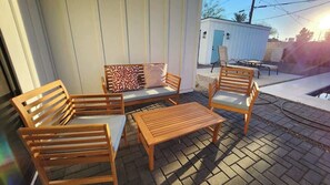A patio with wooden furniture, including a sofa and chairs, and a small table.