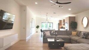 Una sala de estar moderna con un sofá seccional, una mesa de centro y un televisor de pantalla plana montado en la pared.