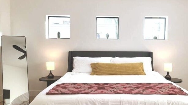 Habitación de hotel con cama, dos mesitas de noche, un espejo y tres cuadros en la pared.