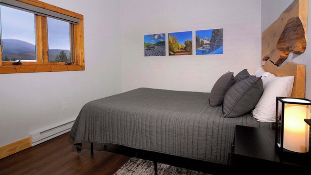 Ein Schlafzimmer mit Bett, Fenster, einem Wandbild und einem Kopfteil.