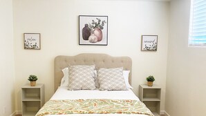 Ein Schlafzimmer mit einem Bett, zwei Nachttischen, einem Deckenventilator und zwei Bildern an der Wand.