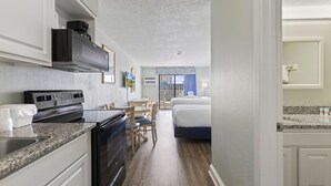 Quarto de hotel compacto com cozinha compacta, cama, área de refeições e vista para a cidade.