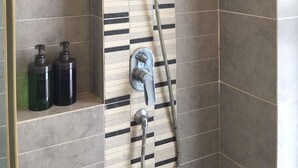 Eine Dusche mit Handbrause und verstellbarem Wasserhahn an der Wand.