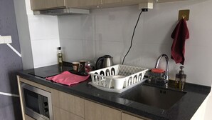 Eine moderne Küche mit eingebauter Mikrowelle, einer Edelstahl-Spüle und einem Wasserkocher.