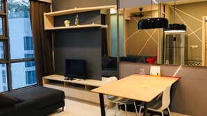Ein modernes Wohnzimmer mit einer Couch, einem Fernseher, einem Esstisch und einer Küchenzeile mit einem Kühlschrank.
