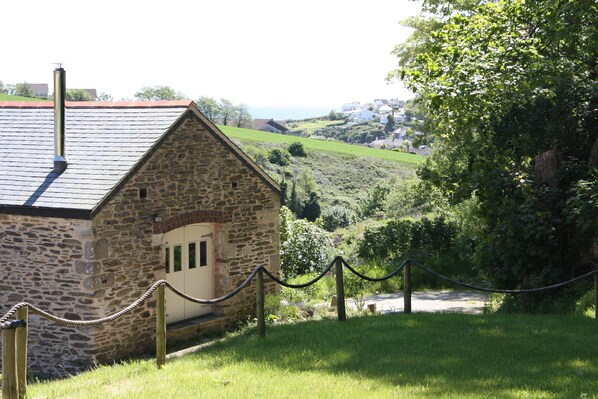 A stone building with a sloped roof, surrounded by greenery and a rope barrier. - Beautiful barn conversion, close to Mevagissey, Portmellon and the SW Coast path (Mevagissey)