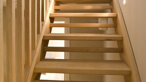 Un escalier en bois au design moderne, menant à l’étage supérieur.