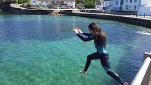 Une personne qui saute dans une eau claire depuis un quai.