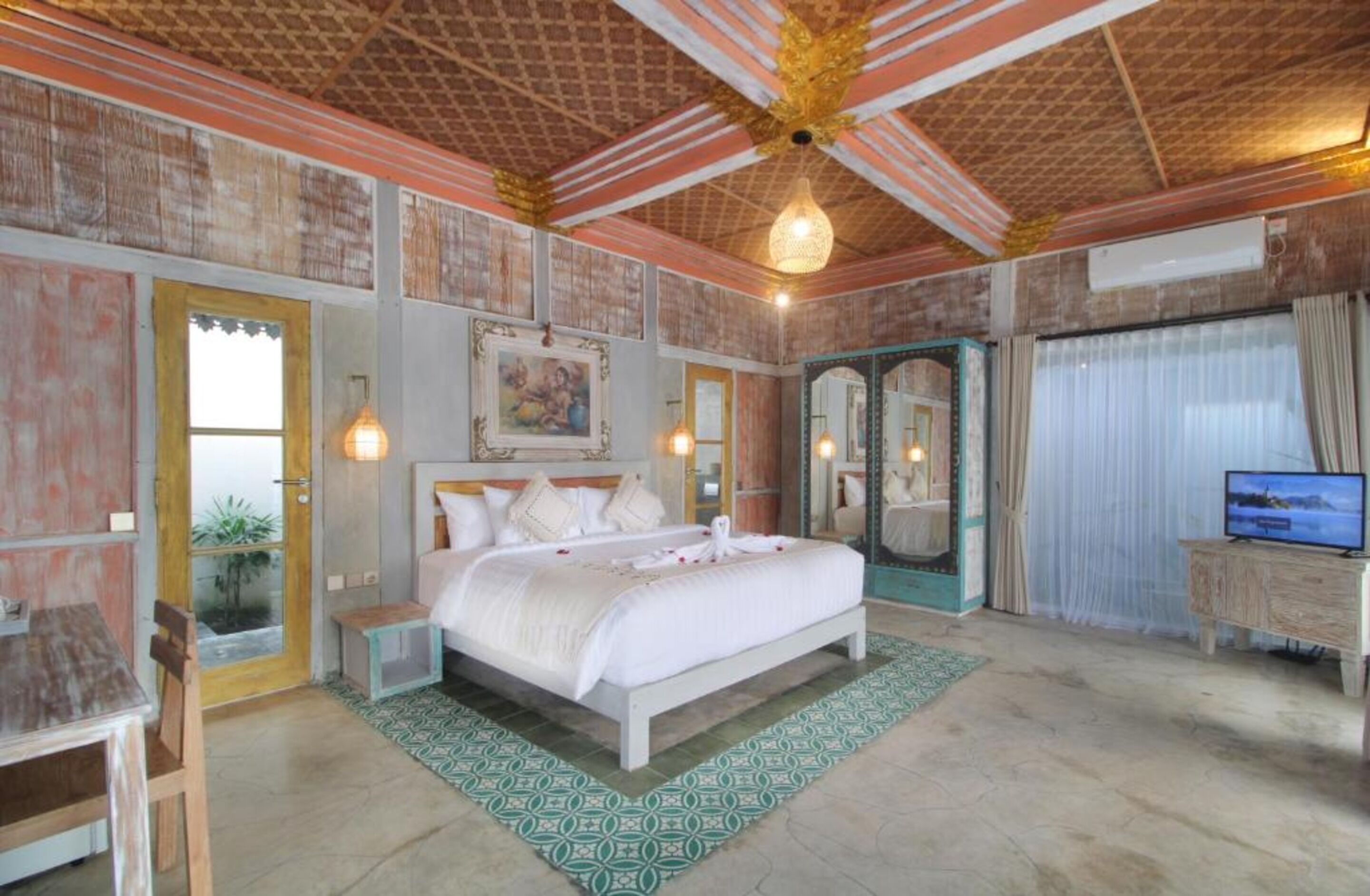 A bedroom with a bed, bedside tables, a television, and a mirror.