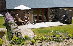 Relax on the patio with a comfortable table and chairs, surrounded by lush greenery and a beautiful garden.