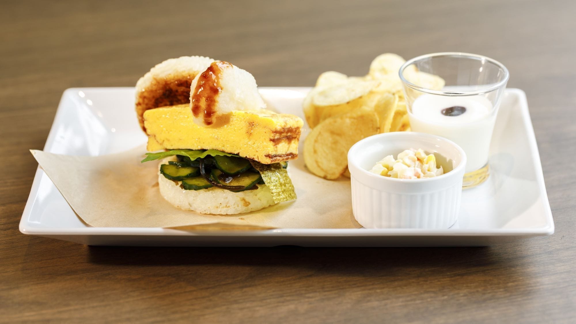 Una bandeja rectangular blanca con un sándwich, papas fritas y un pequeño bol de salsa.