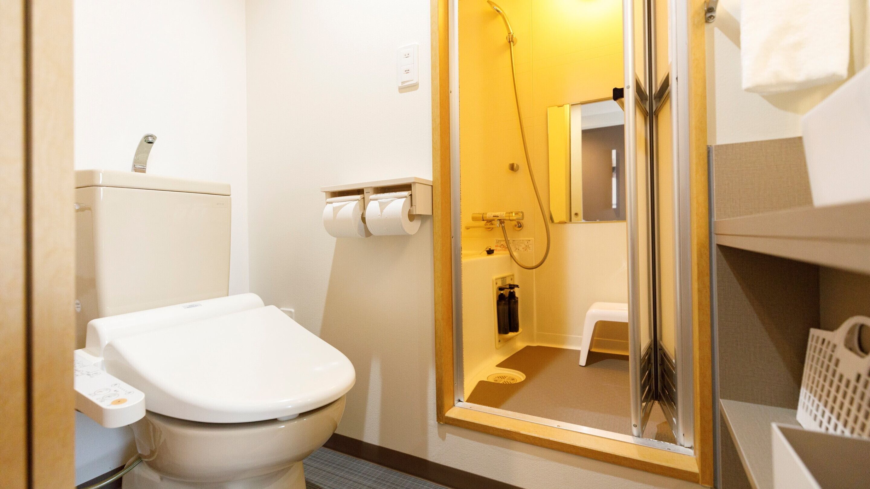 Un baño pequeño con inodoro, cabina de ducha y un espejo reducido.