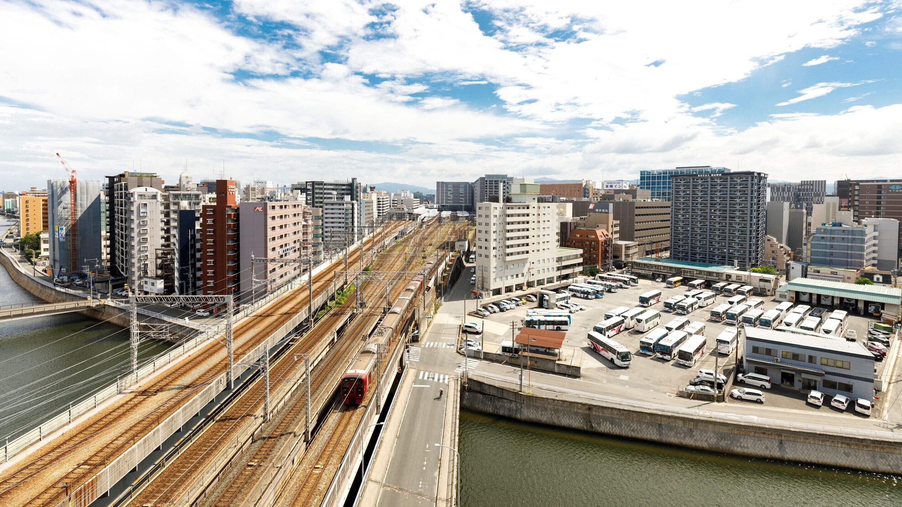 Un immeuble de grande hauteur doté d’une architecture moderne, situé dans un quartier urbain à proximité d’une gare et d’un parking.