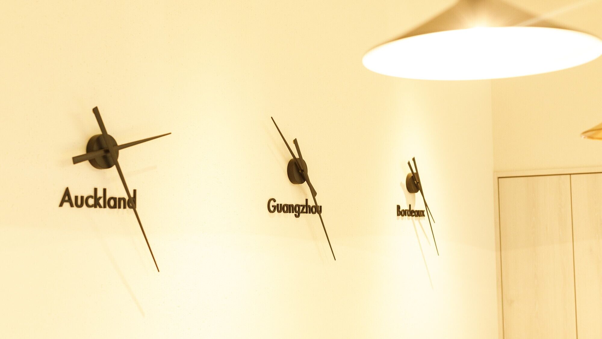 Three wall clocks labeled with city names: Auckland, Guangzhou, and Bordeaux.