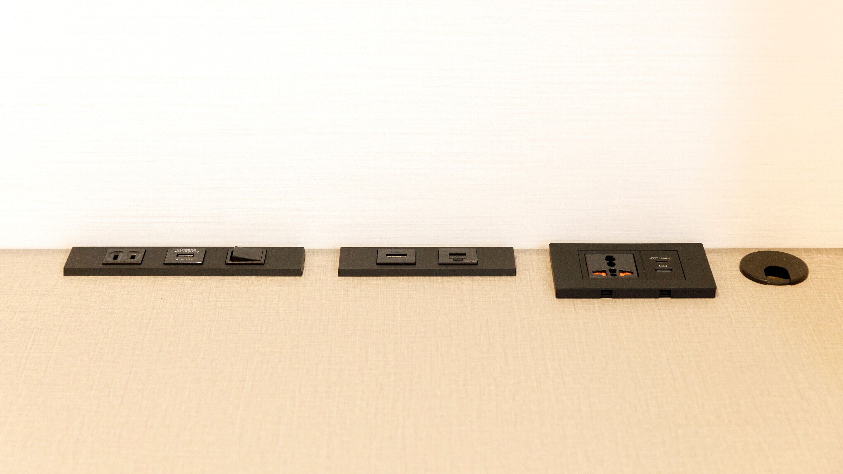 Three electrical outlets and a USB port on a beige wall.