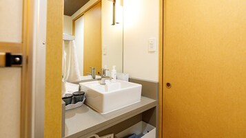 Un baño de hotel con un lavamanos blanco, un espejo y una toalla colgada en la pared.