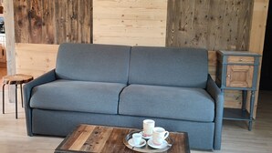 Una sala de estar moderna con un sofá gris, una mesa de centro de madera con tazas y platillos, y un mueble pequeño.