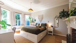Une chambre à coucher avec un grand lit, des tables de chevet, un bureau et une cheminée.
