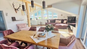 A dining area with a wooden table, pink upholstered chairs, and pendant lights. - 5* Lory vacation apartment with castle and panoramic views (Halblech)