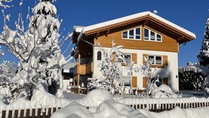 A two-story house with a wooden facade and a snow-covered roof. - 5* Lory vacation apartment with castle and panoramic views (Halblech)