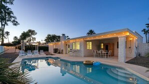 A modern house with a swimming pool, outdoor seating, and string lights.