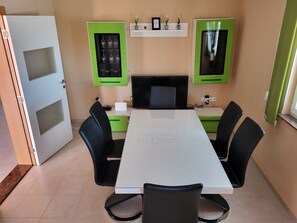 A conference room with a white table, black chairs, green cabinets, and a black monitor.