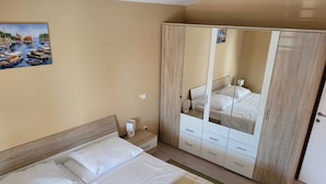 Un dormitorio con cama, mesita de noche, armario y un cuadro en la pared.