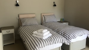 A double bed with striped bedding, two bedside tables, a nightstand, and two wall-mounted lamps.