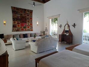 Amplia sala de estar con un gran tapiz mural, un conjunto de sofás, un aparador de madera y una cama.
