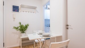 Un espace repas moderne avec une table blanche, des chaises et une plante en pot.