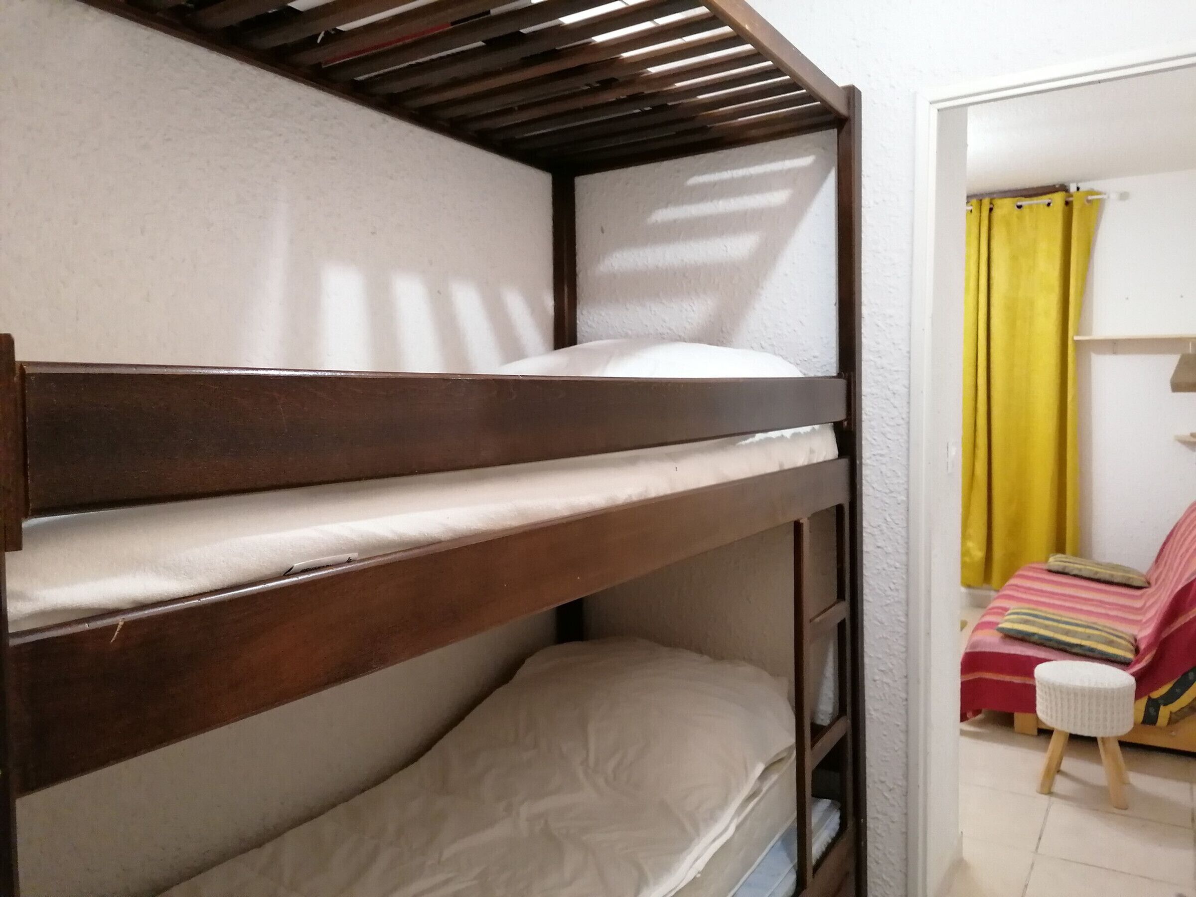 A bunk bed with a wooden frame and white bedding.