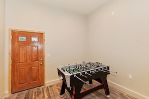 Una habitación con puerta de madera y una mesa de fútbol de mesa.