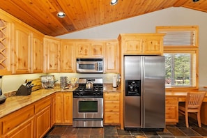 Una cocina con gabinetes de madera, un refrigerador de acero inoxidable, un microondas y una estufa.
