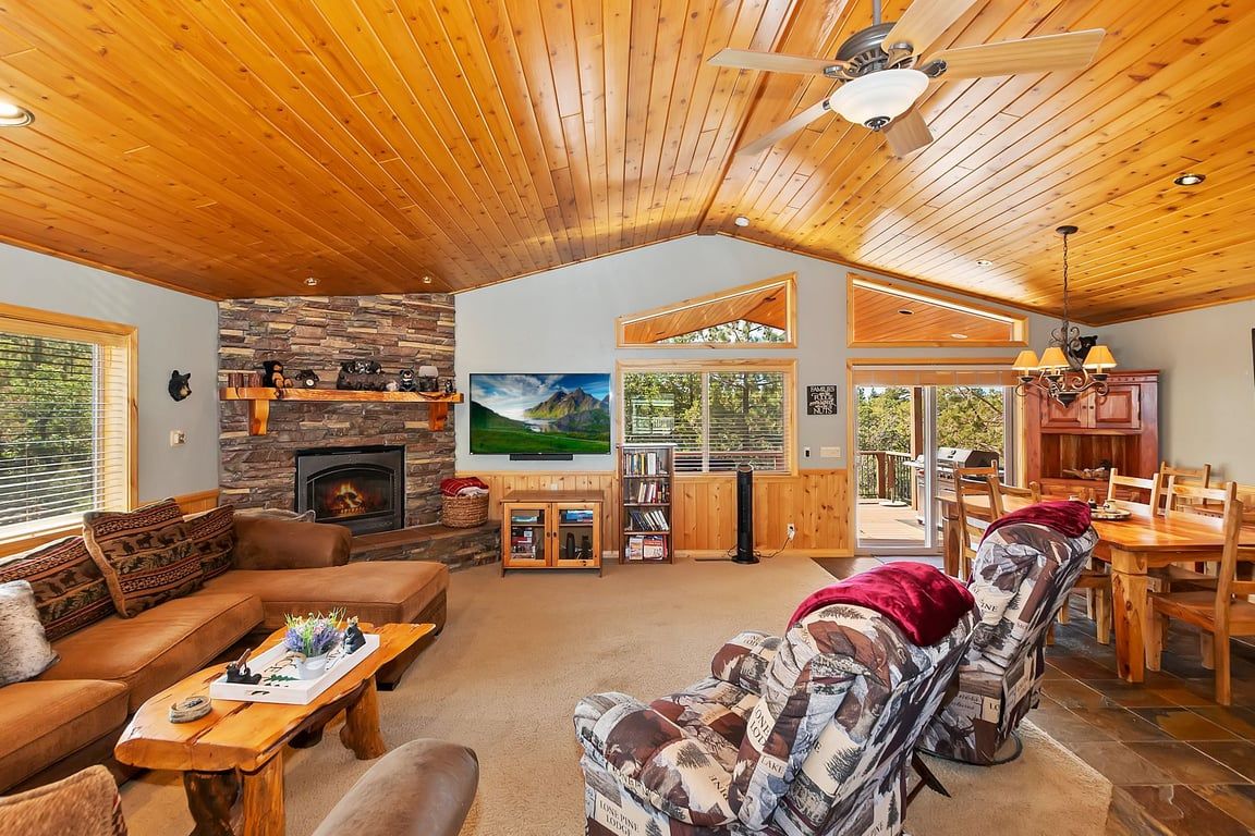 A cozy living room with a fireplace, a large TV, and a dining area with wooden furniture.