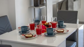 A breakfast table with various drinks and pastries.