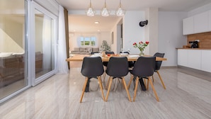 Un comedor moderno con una mesa grande, cuatro sillas y un jarrón de flores.