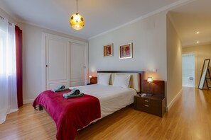 Een keurig opgemaakte slaapkamer met een groot bed, een nachtkastje met een lamp en een kledingkast.