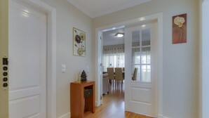 A hallway with wooden flooring, white walls, and a door leading to a dining area with a table and chairs. - Jazz & Silvia (Albufeira)