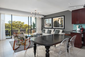 Relax in this stylish living space with a large dining table, comfortable sofa, and a view of lush greenery.