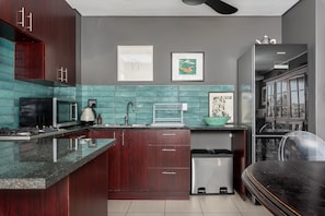 Enjoy cooking in this well-equipped kitchen with a sleek island, dark cabinets, and a stainless steel sink.