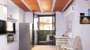 A compact kitchen with a refrigerator, a flat-screen TV, and a dining area with a table and chairs.