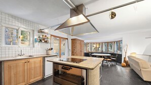Eine moderne Küche mit Kochinsel, Holdschränken, einem integrierten Backofen und einem Essbereich mit rundem Tisch und Stühlen.