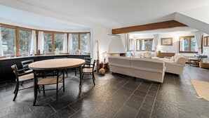 Ein geräumiges Wohnzimmer mit einem großen runden Tisch, einer Couch und einem Kamin.