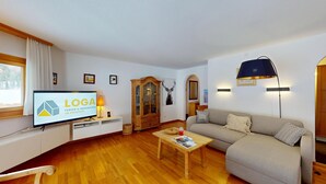 A living room with a television, wooden cabinet, sofa, and a lamp. - Beautiful 2-room apartment on the raised ground floor with approx. (Champfèr)