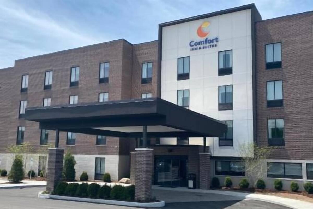 A Comfort Inn & Suites hotel with a brick facade, a covered entrance, and a landscaped front yard.